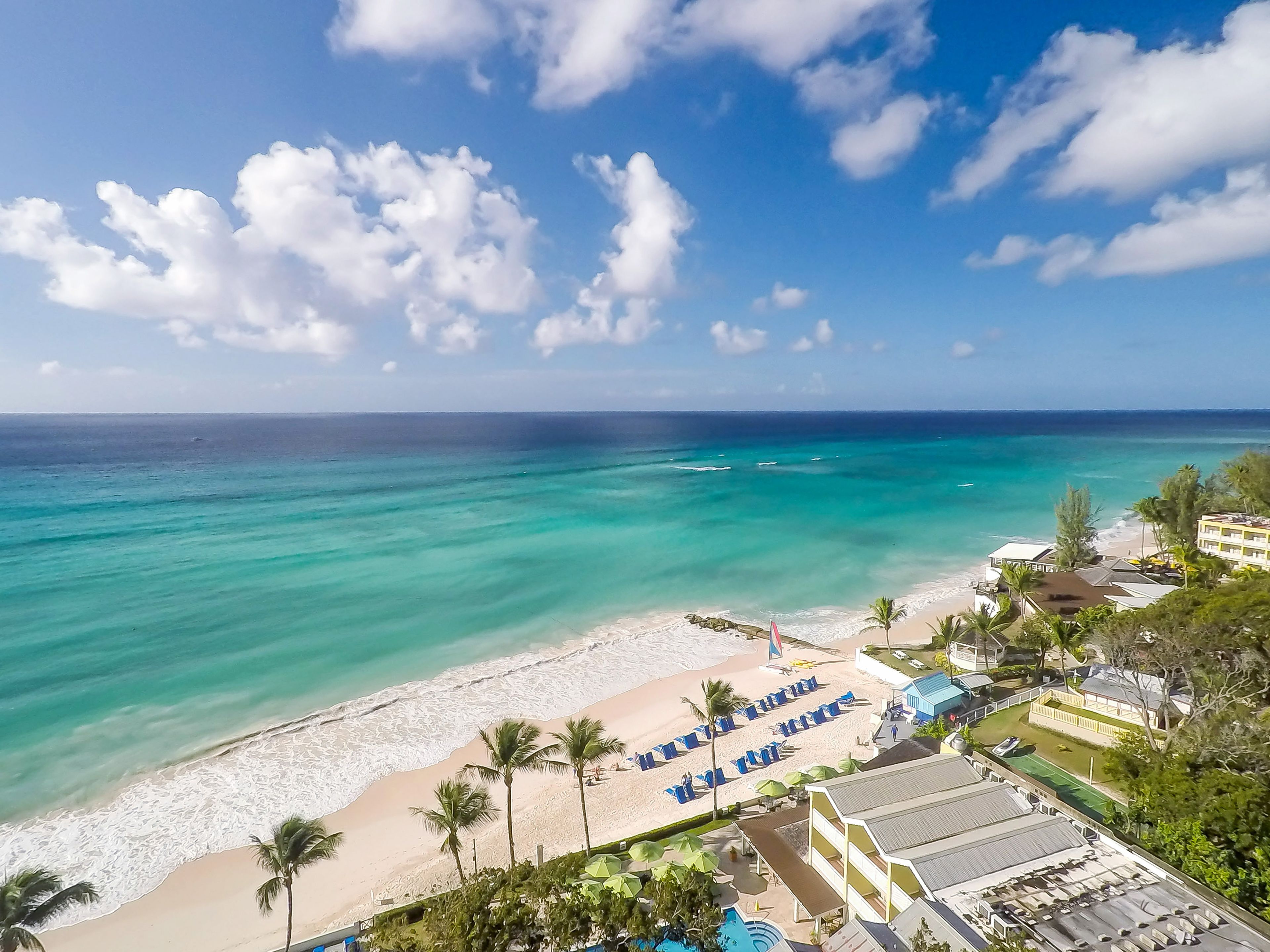 Un resort en la playa con piscina, sillas de playa y vistas al océano.