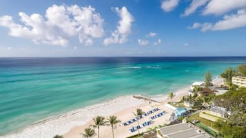Un resort en la playa con piscina, sillas de playa y vistas al océano.