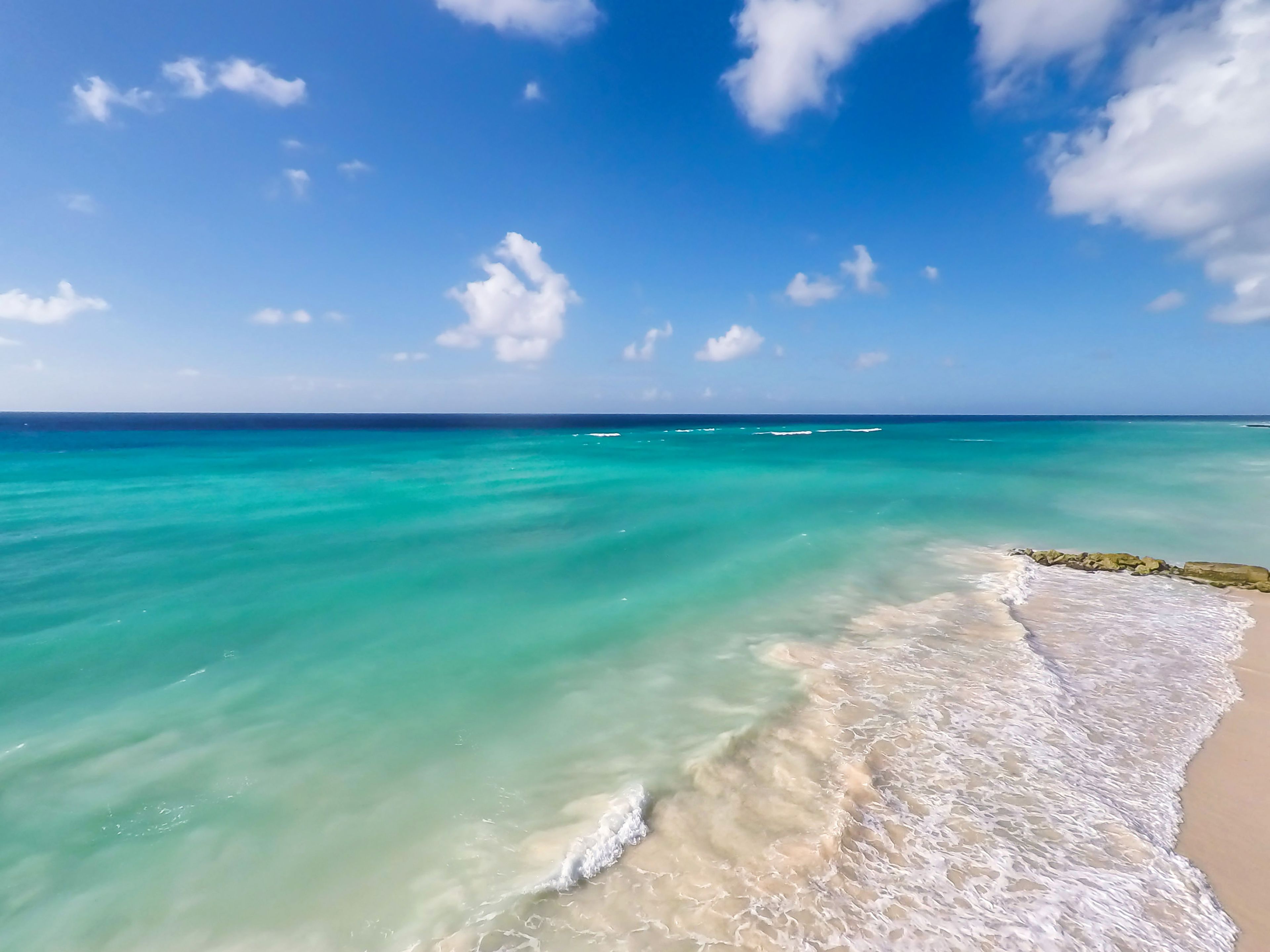 A beach with clear turquoise waters and a sandy shore.