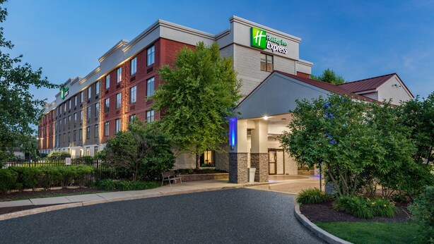 Un hôtel Holiday Inn Express avec une façade en briques, de grandes fenêtres et une pelouse bien entretenue.