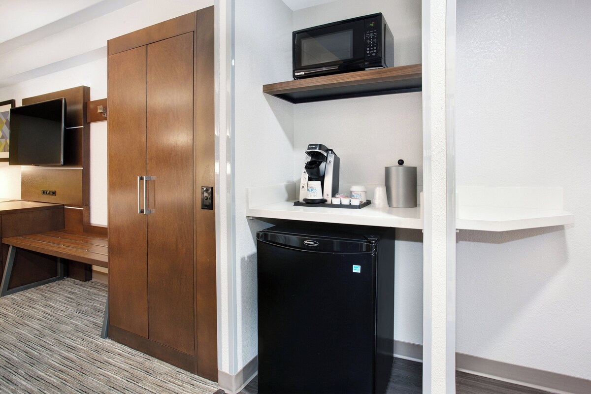 A compact kitchenette with a microwave, coffee maker, and refrigerator.