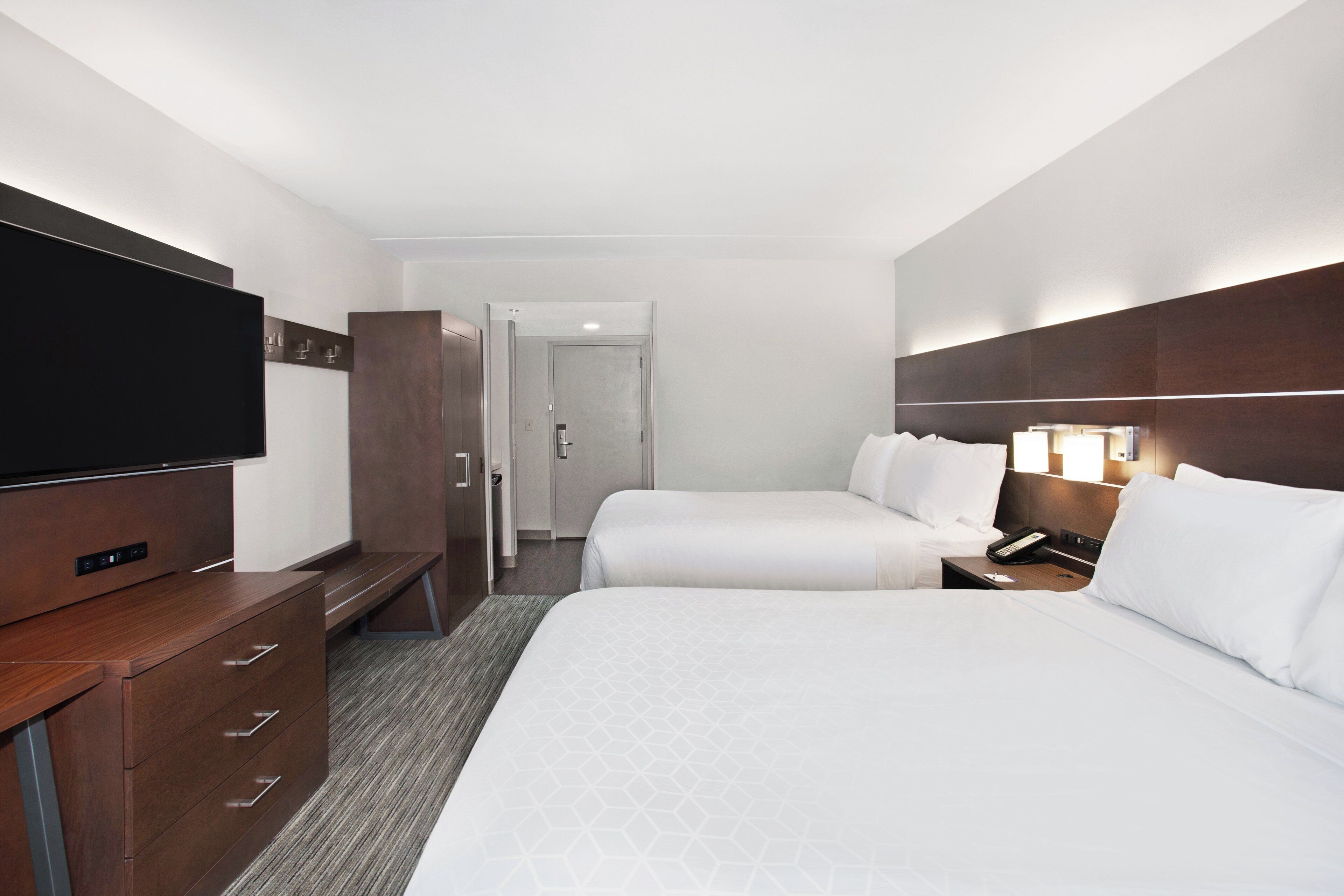A hotel room with a TV, two beds, a desk, and a wardrobe.