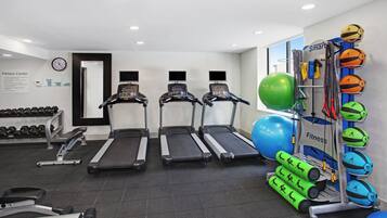 A fitness center with treadmills, dumbbells, exercise balls, and resistance bands.