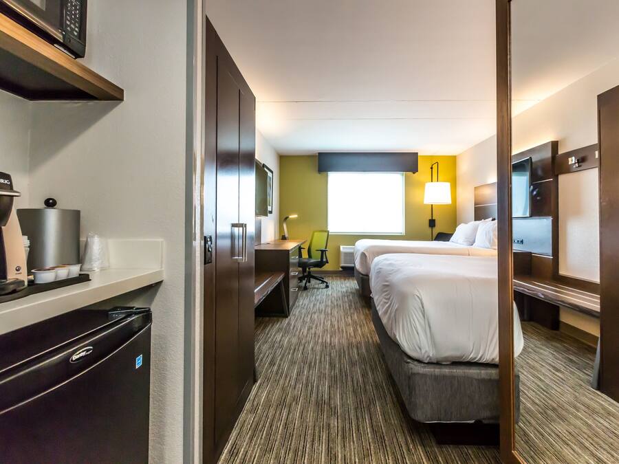 Habitación de hotel con kitchenette, cama, escritorio y silla.