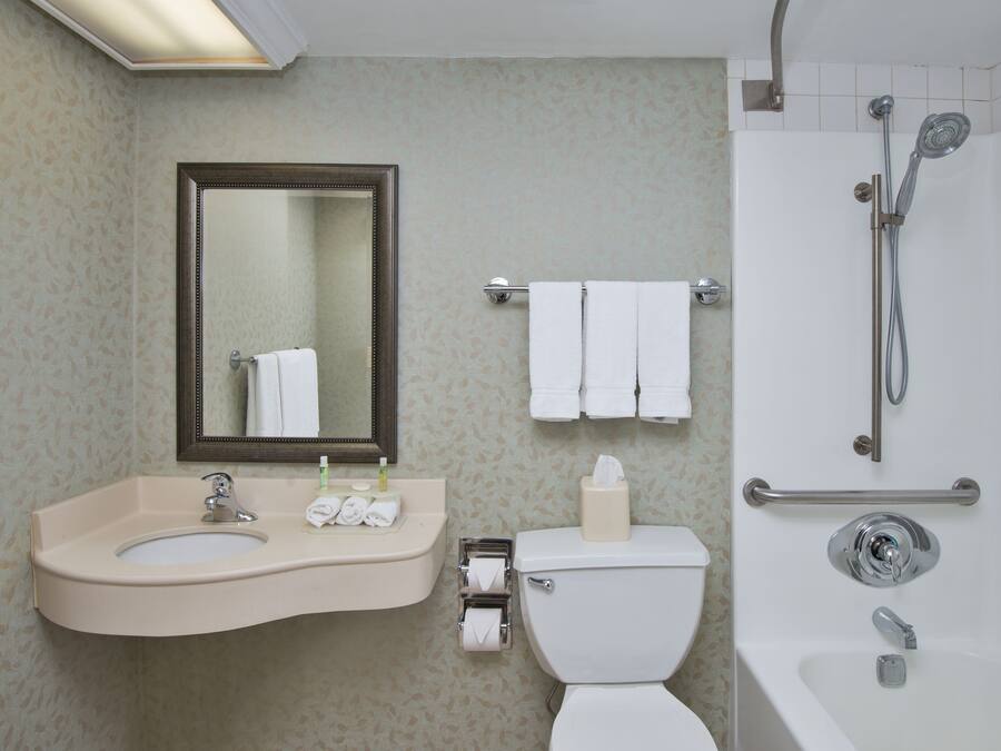 A bathroom with a sink, mirror, toilet, and shower.