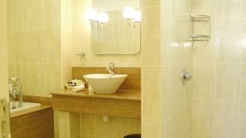 A bathroom with a sink, mirror, toilet, and bathtub.
