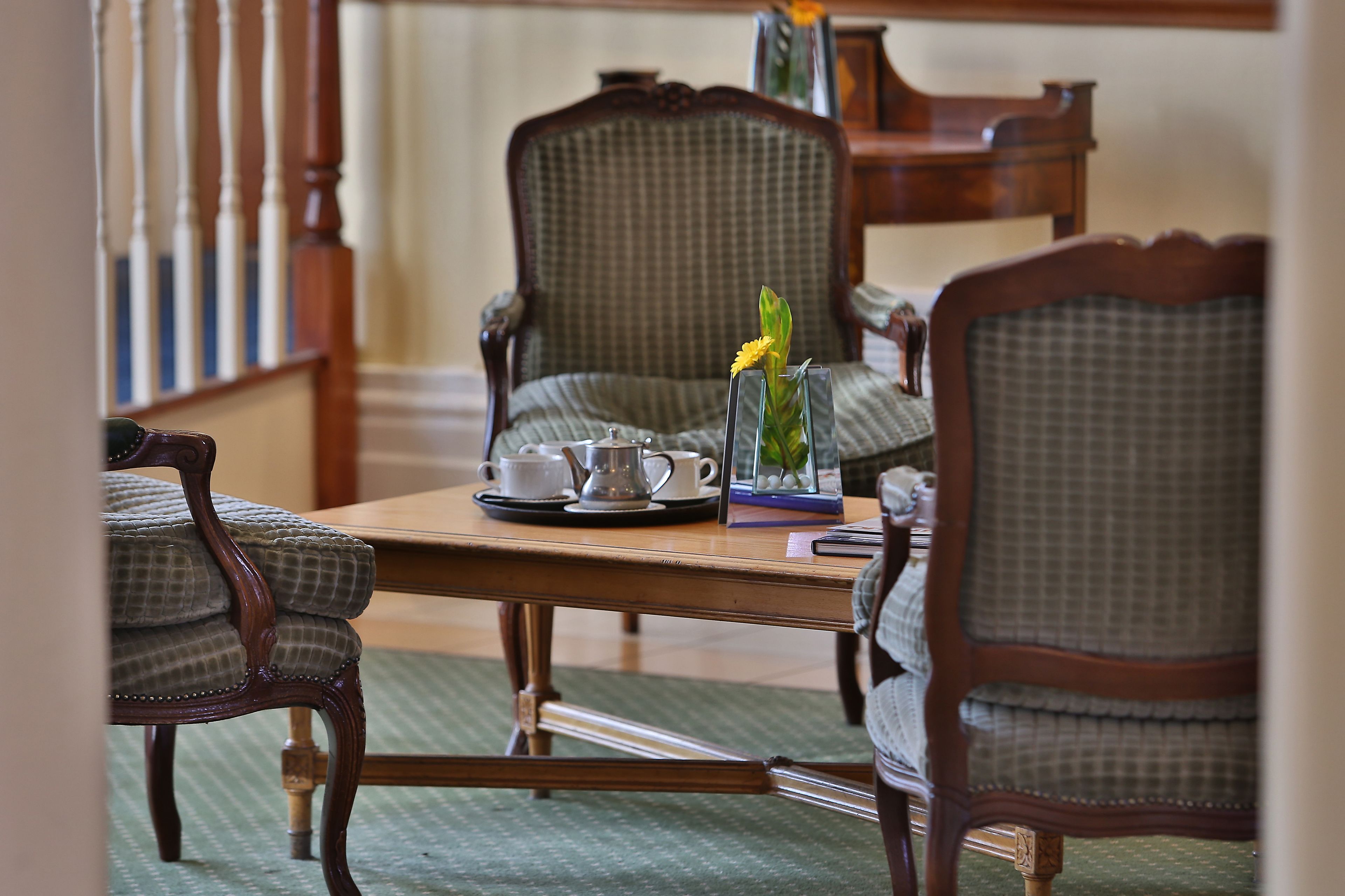A dining area with a wooden table, checkered chairs, and a tray with a teapot and cups.