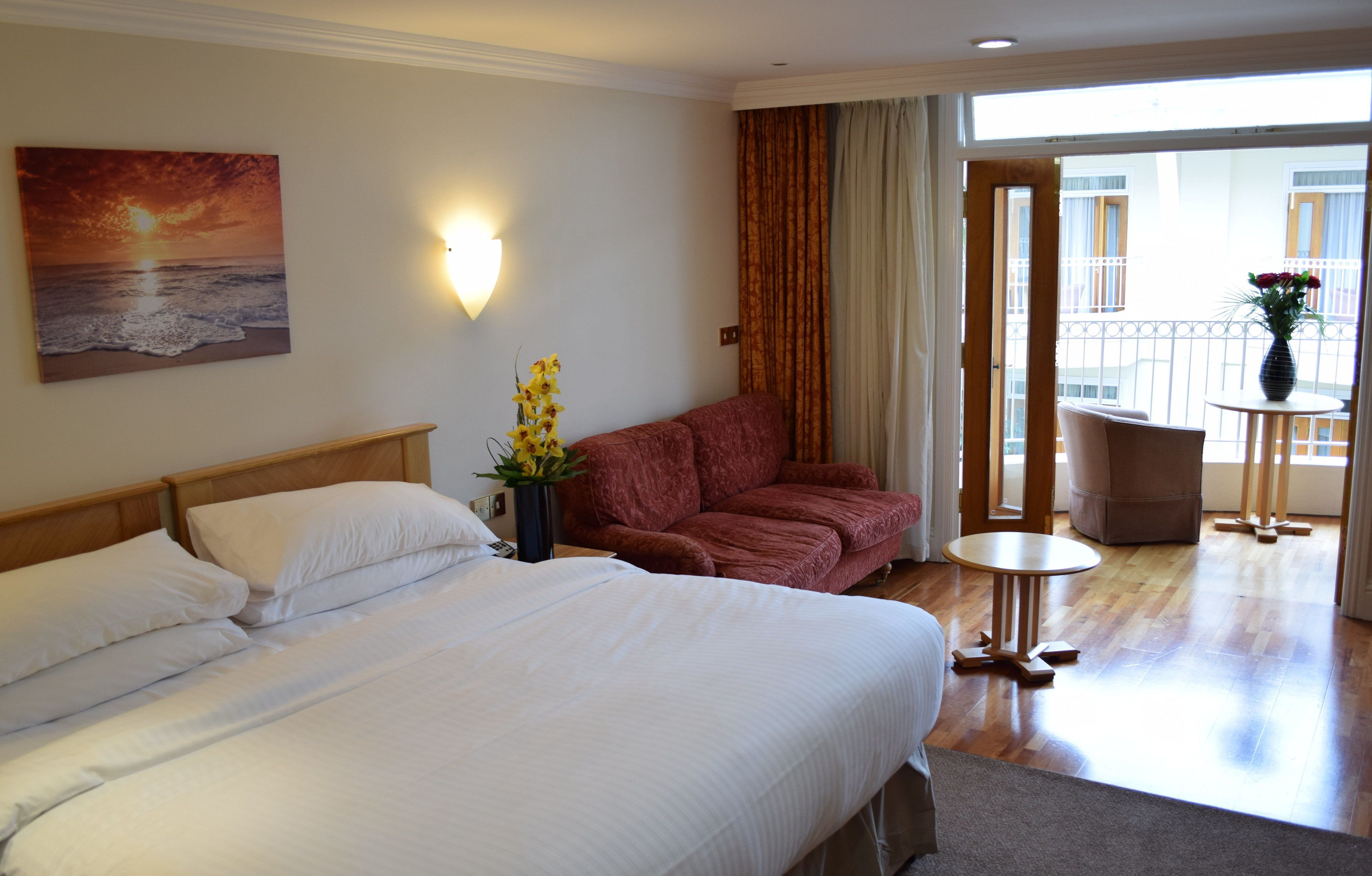 Habitación de hotel con cama, sofá, una mesita y balcón con vistas.