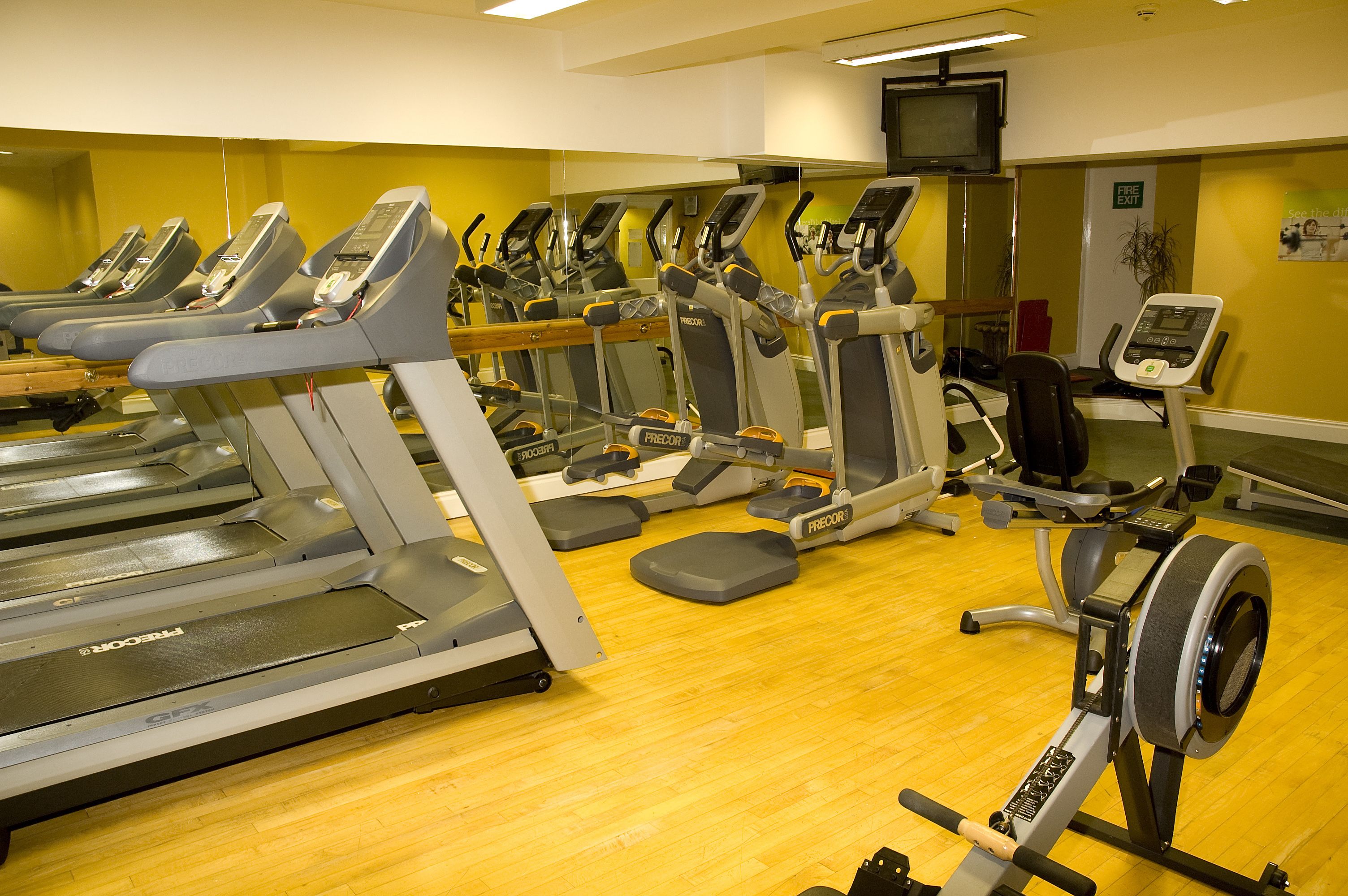 Une salle de sport équipée de plusieurs tapis de course, de plusieurs appareils elliptiques et d’un vélo d’appartement.