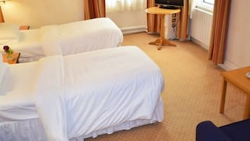 Habitación de hotel con dos camas individuales, una mesita, un televisor y una ventana con cortinas.