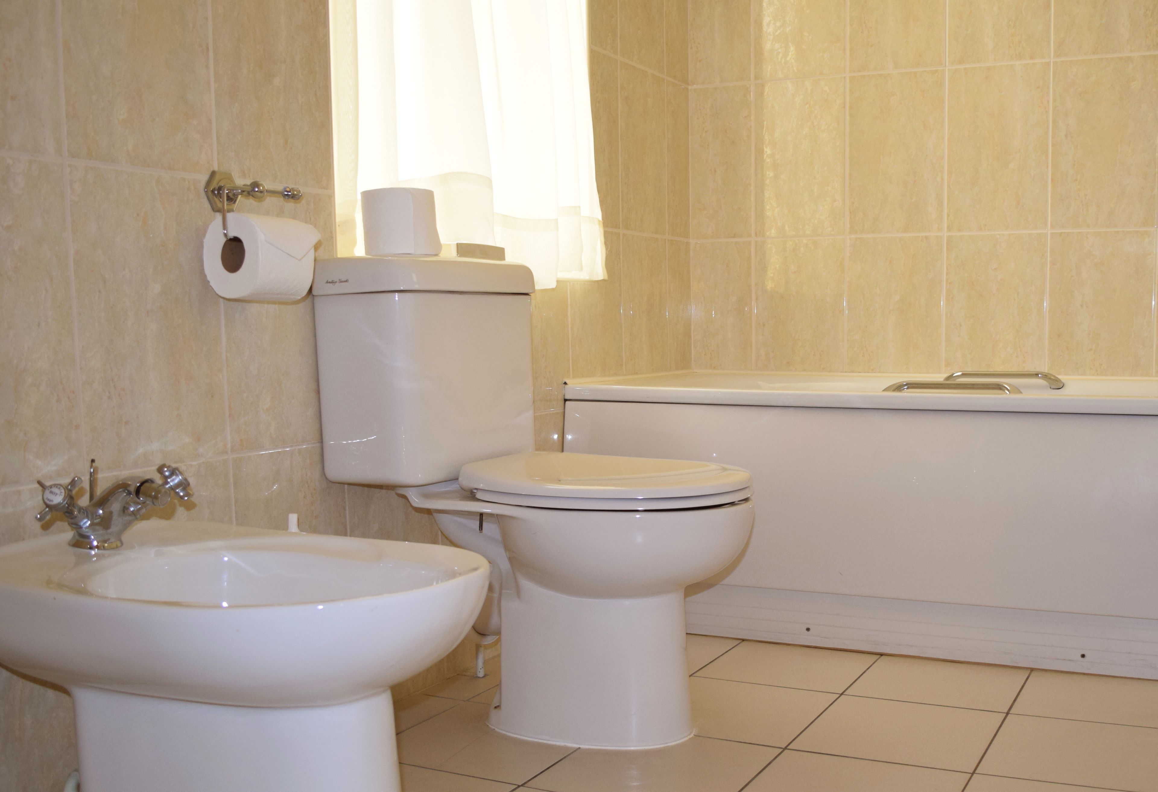 A bathroom with a toilet, bidet, and bathtub.