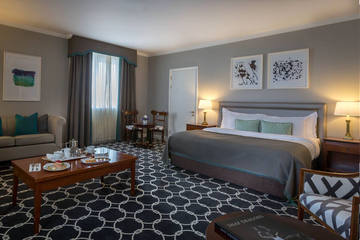 Une chambre d’hôtel avec un lit, un canapé, une table basse et des œuvres d’art accrochées aux murs.