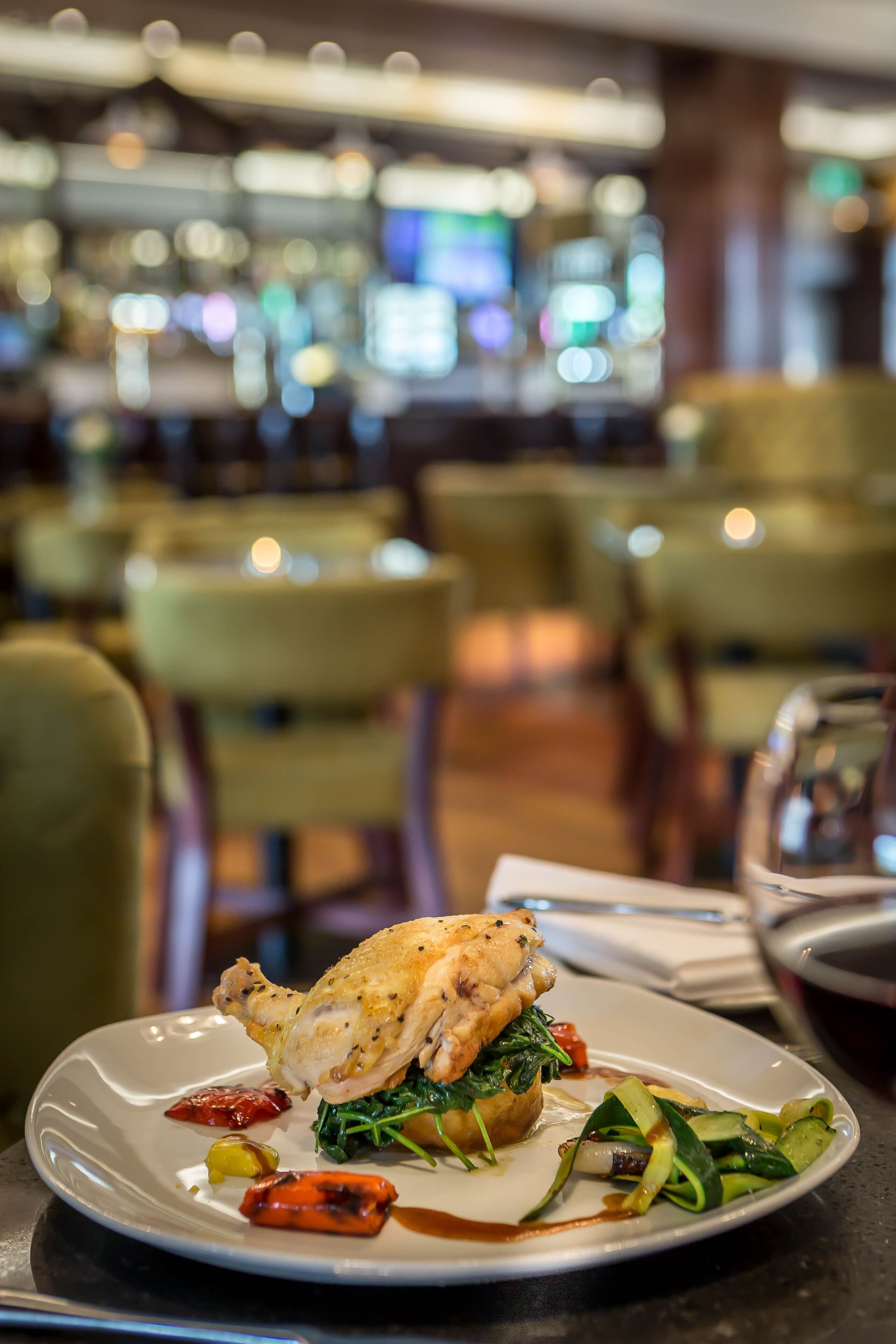 A dining table with a plate of food, a wine glass, and a menu.