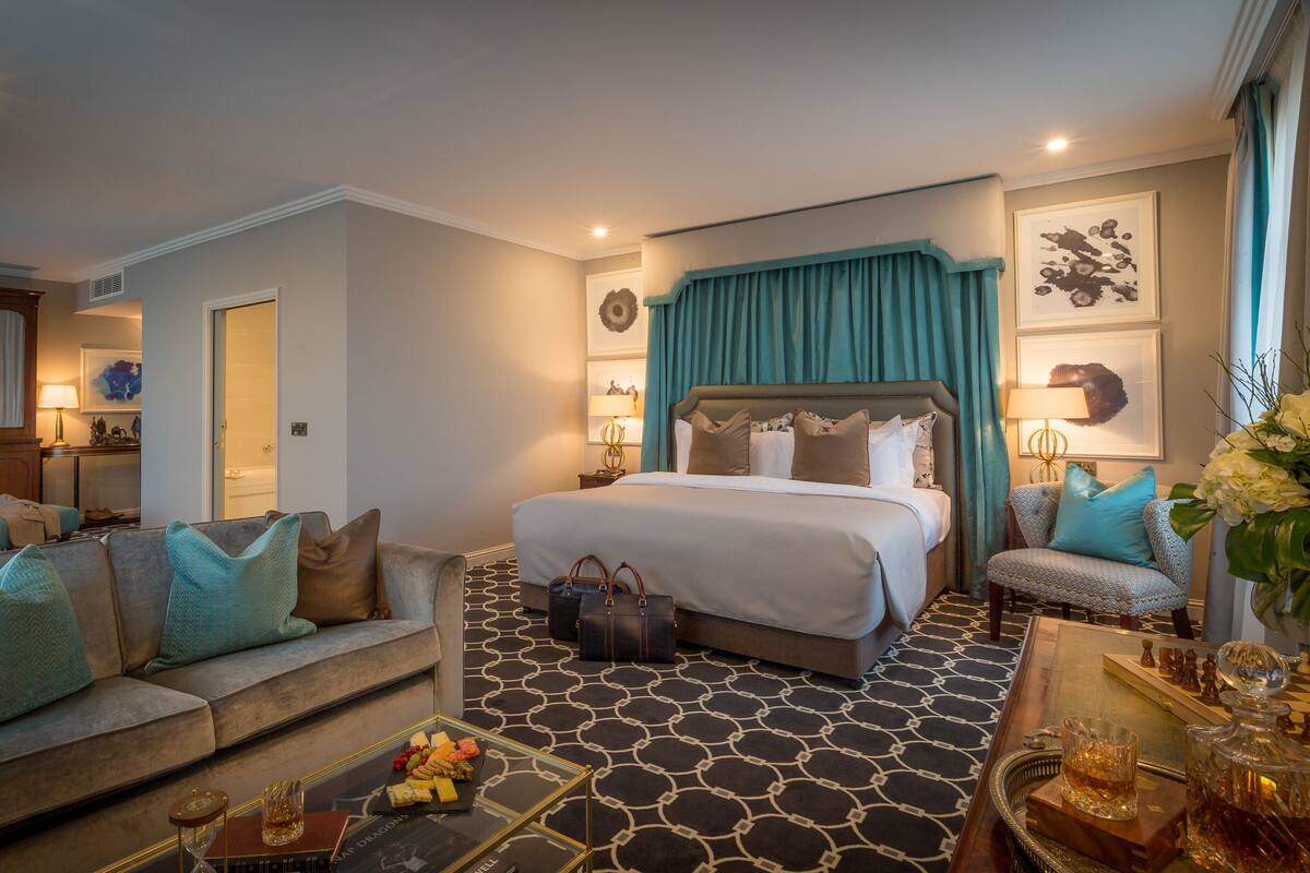 Une chambre d’hôtel avec un grand lit, un canapé, une table basse avec des collations et un jeu d’échecs.