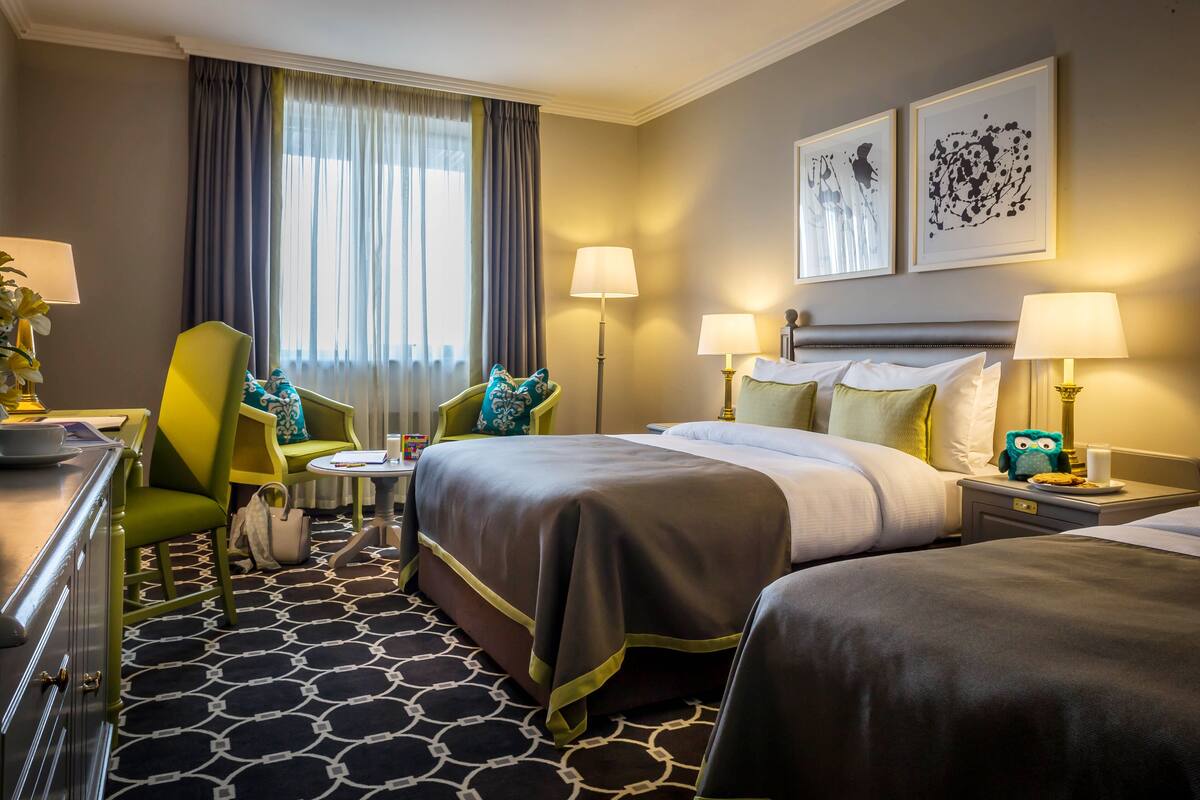 Une chambre d’hôtel avec un lit, deux chaises, un bureau et une lampe.