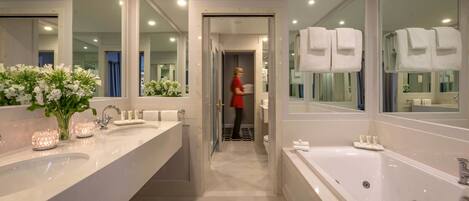 A modern bathroom with dual sinks, a large bathtub, and a mirror reflecting the room.