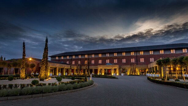Un hotel con fachada simétrica, numerosas ventanas y una entrada bien iluminada.