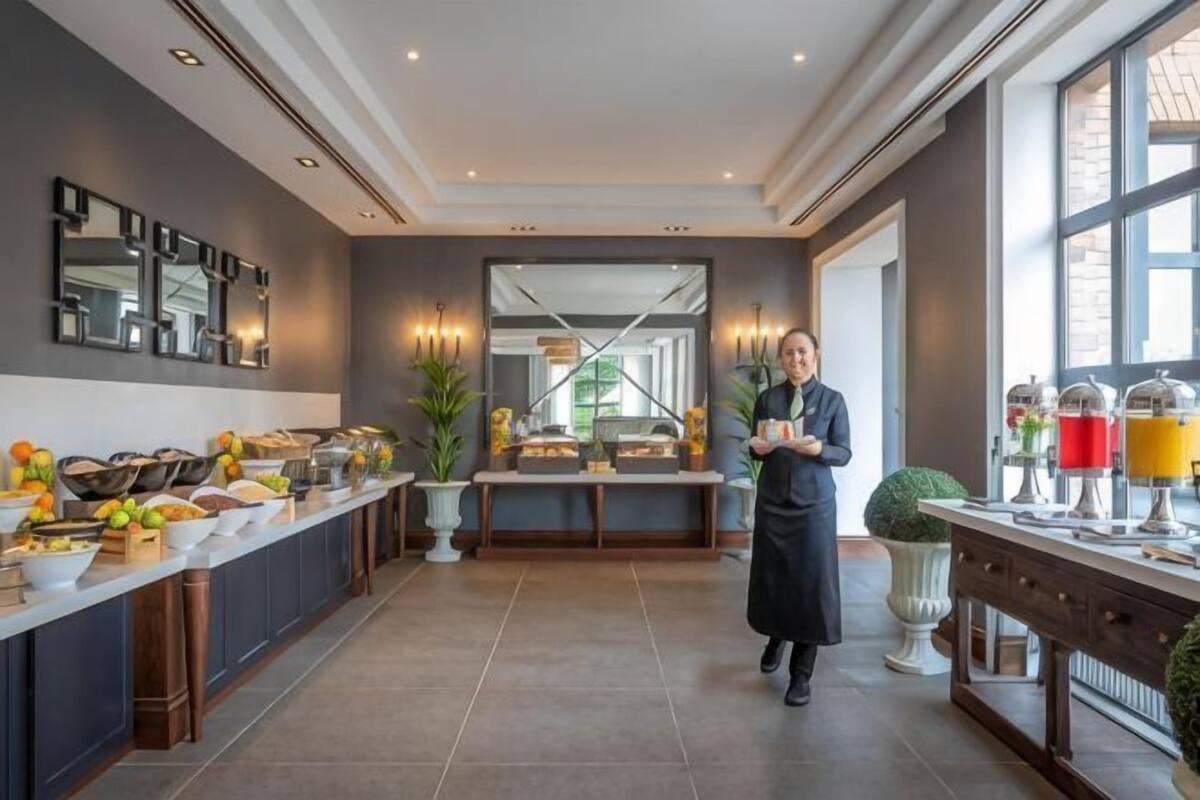 Une cuisine moderne avec un long comptoir, une personne en uniforme et une grande fenêtre.