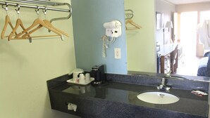 Ein Badezimmer mit Waschbecken, Handtuchspender und einem an der Wand befestigten Föhn.