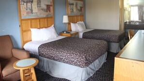 Ein Hotelzimmer mit zwei Betten, einem kleinen runden Tisch, einem Stuhl und einem Schreibtisch.