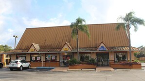 Ein Inn in Tampa mit einem braunen Metall-Dach, Palmen und einem Parkplatz.