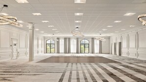 A spacious room with a large carpet, high ceilings, and large windows.