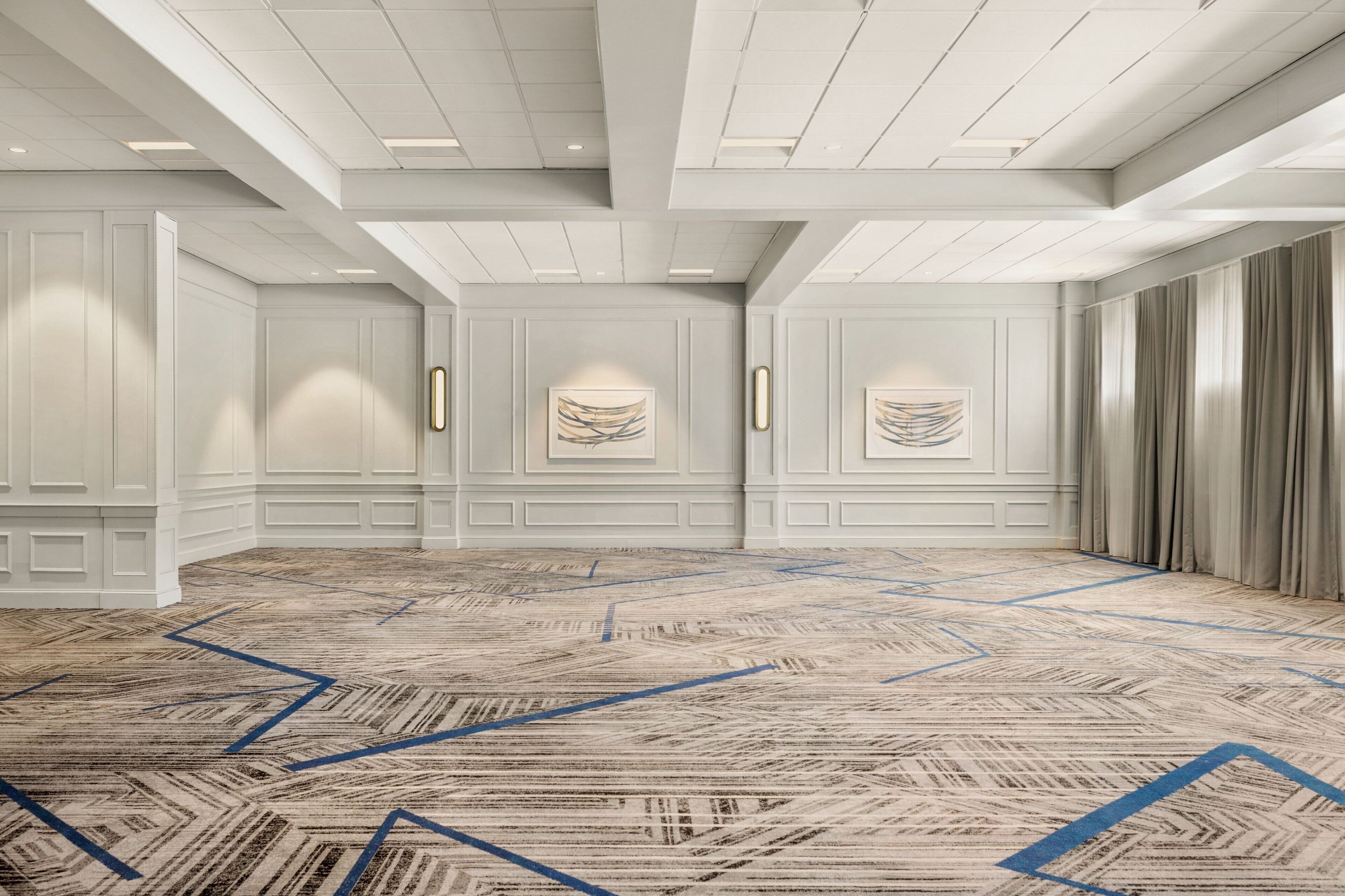 A spacious room with a patterned carpet, white walls, and a ceiling with recessed lighting.