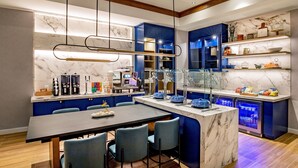 A modern kitchen with marble countertops, blue cabinetry, and a central island with seating.