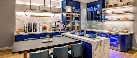 A modern kitchen with marble countertops, blue cabinetry, and a central island with seating.