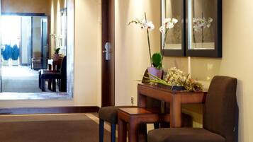 Un vestíbulo de hotel con una recepción, dos sillas, una mesita y una planta en maceta.