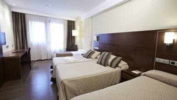 A hotel room with two beds, a desk, and a chair.
