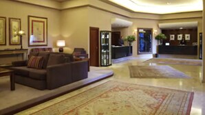 A spacious lobby with a sofa, a reception desk, and framed artwork on the walls.