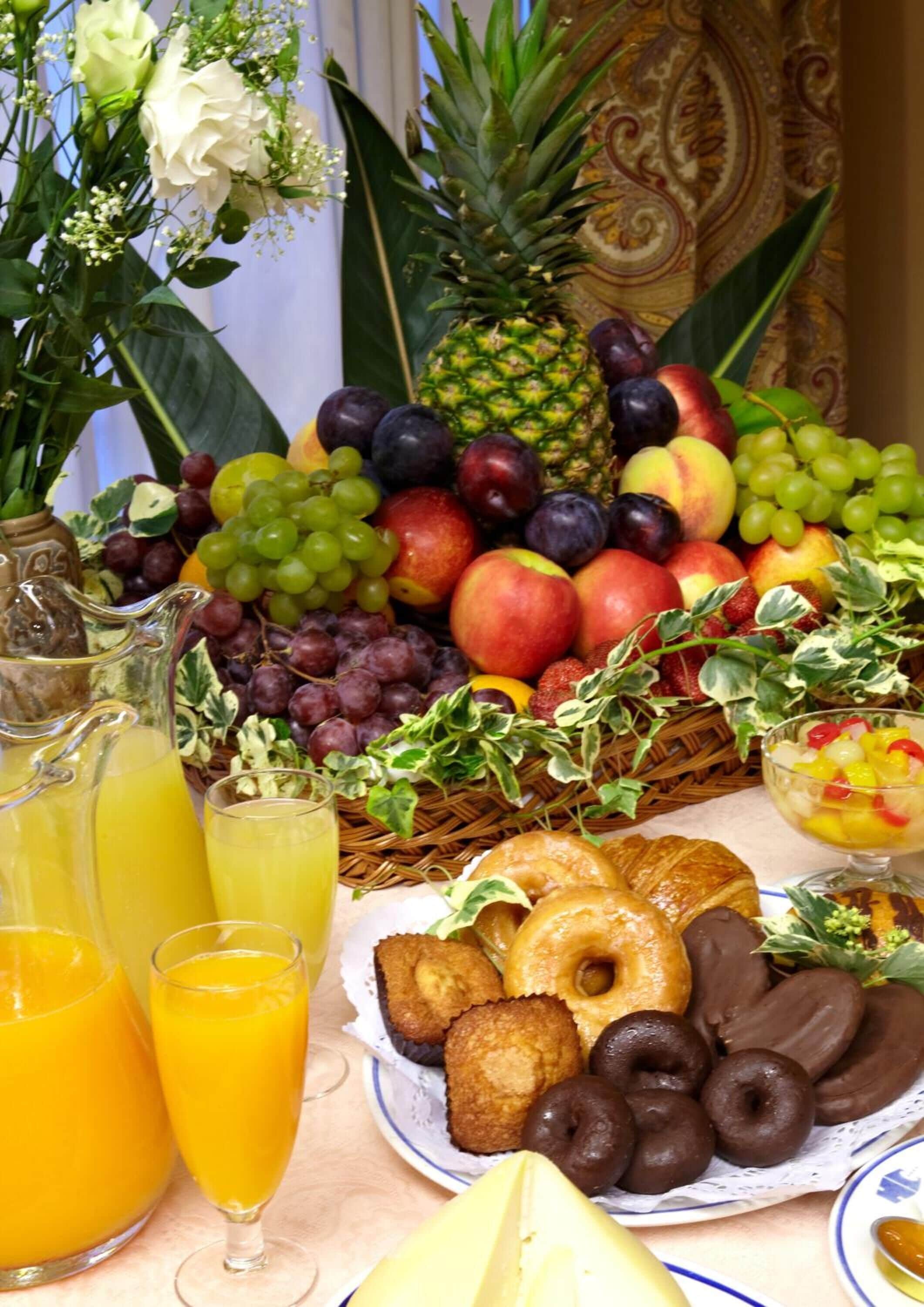 Een tafel met verschillende soorten fruit, gebak en drankjes.