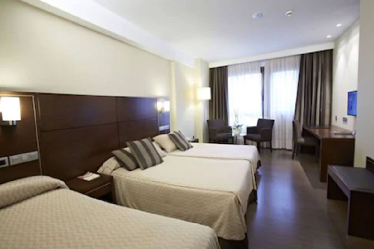 Een hotelkamer met twee bedden, een bureau, een stoel en een televisie.