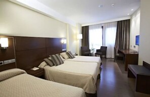 Habitación de hotel con dos camas, un escritorio, una silla y un televisor.