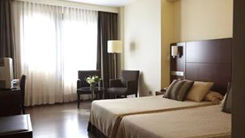 Une chambre d’hôtel avec un grand lit, un bureau avec une chaise, une petite table avec une lampe et un téléviseur fixé au mur.
