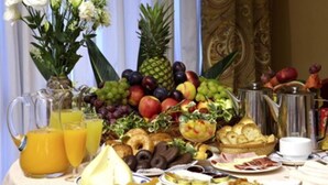 A breakfast buffet with various fruits, pastries, and beverages.