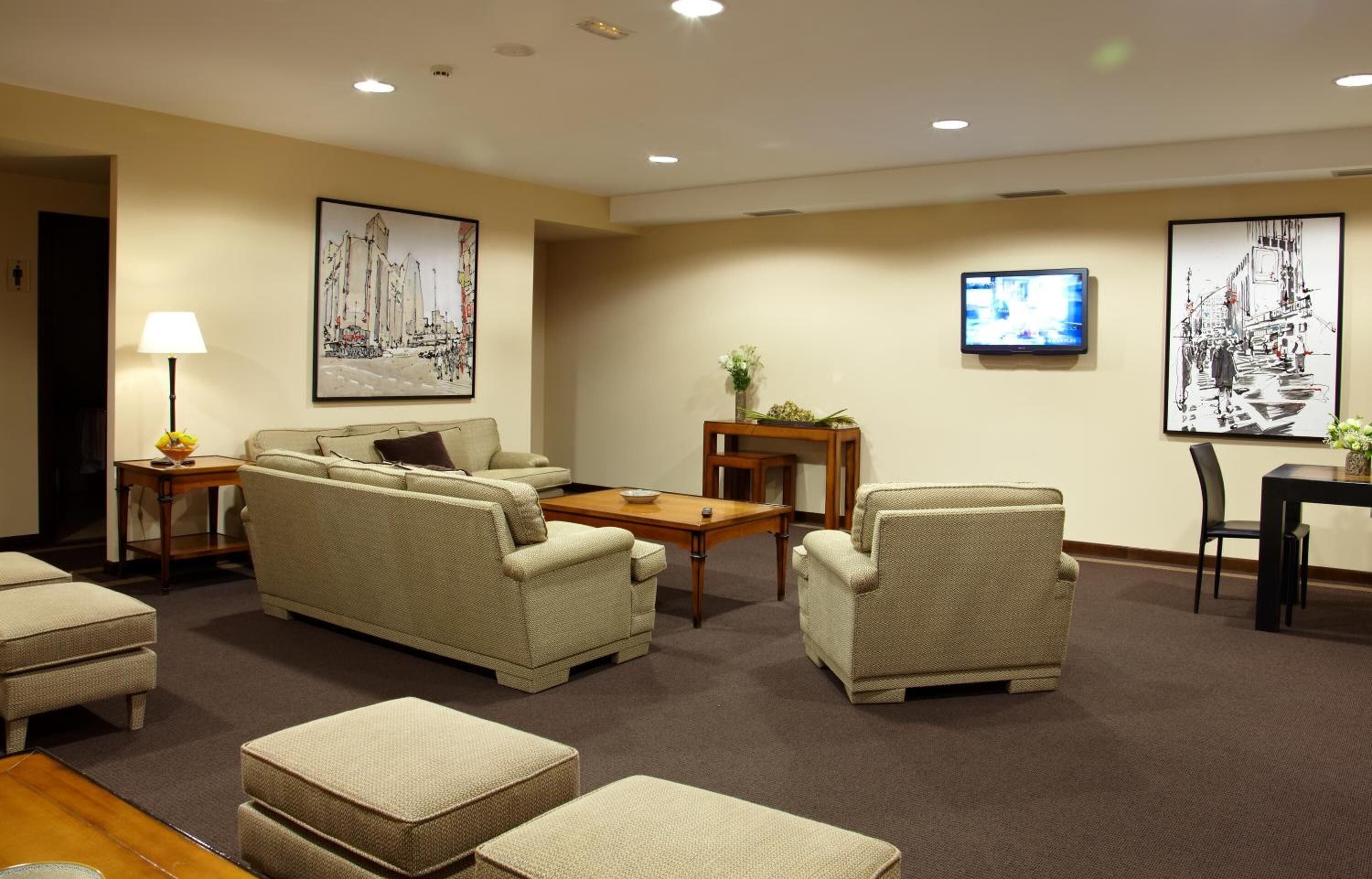 Un hall de hotel con un conjunto de sofás, una mesa de centro, un televisor y obras de arte en las paredes.