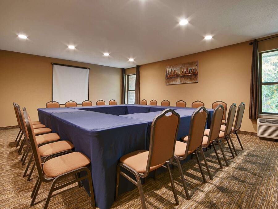 A conference room with a long table, chairs, a projector screen, and a painting on the wall.