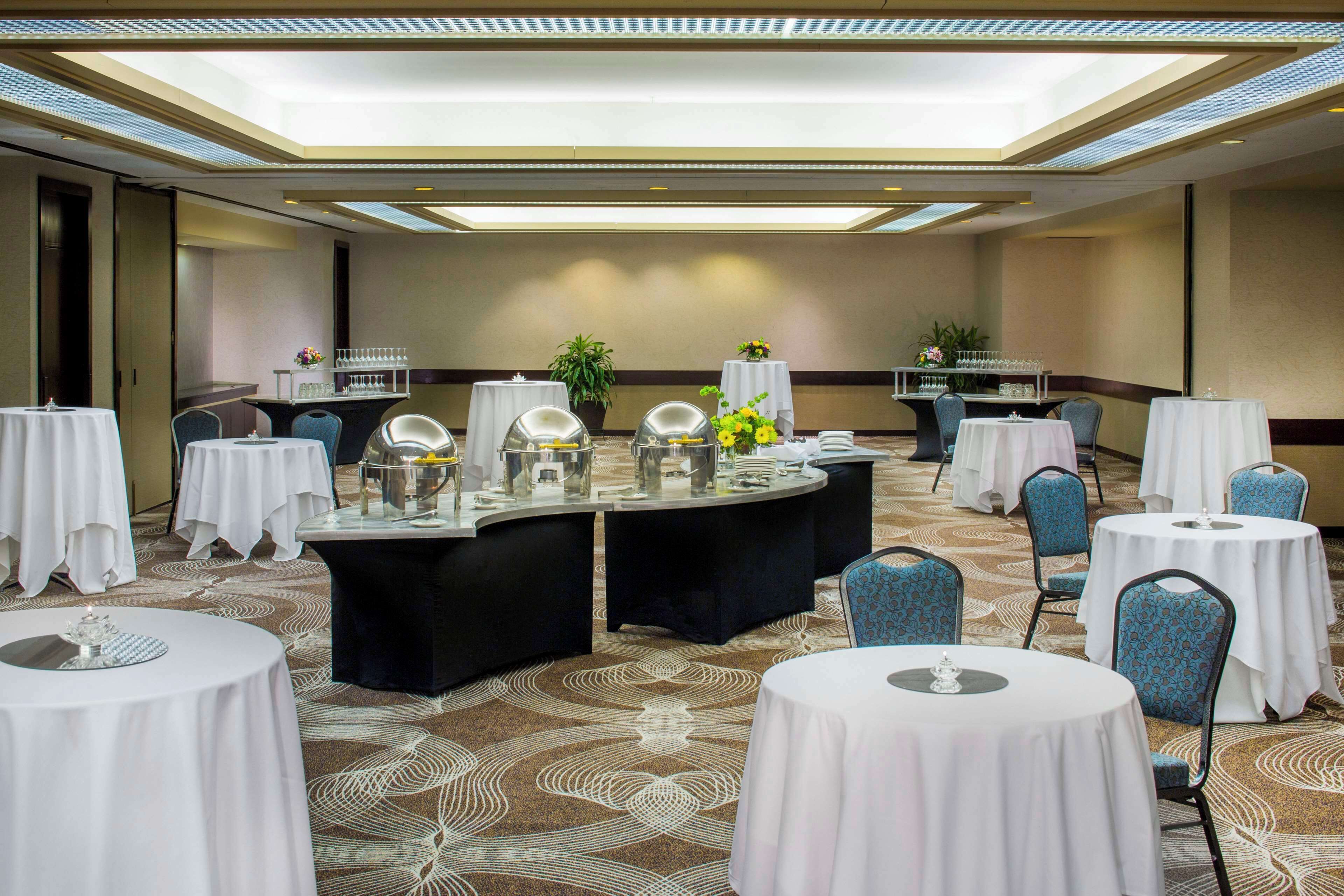 Un salón de conferencias con mesas redondas, sillas y un escenario.