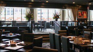 A restaurant with multiple tables and chairs, large windows with curtains, and a chandelier. - Hyatt Regency Buffalo / Hotel and Conference Center (Buffalo)