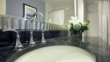 A bathroom with a sink, two faucets, a mirror, and a shower curtain.