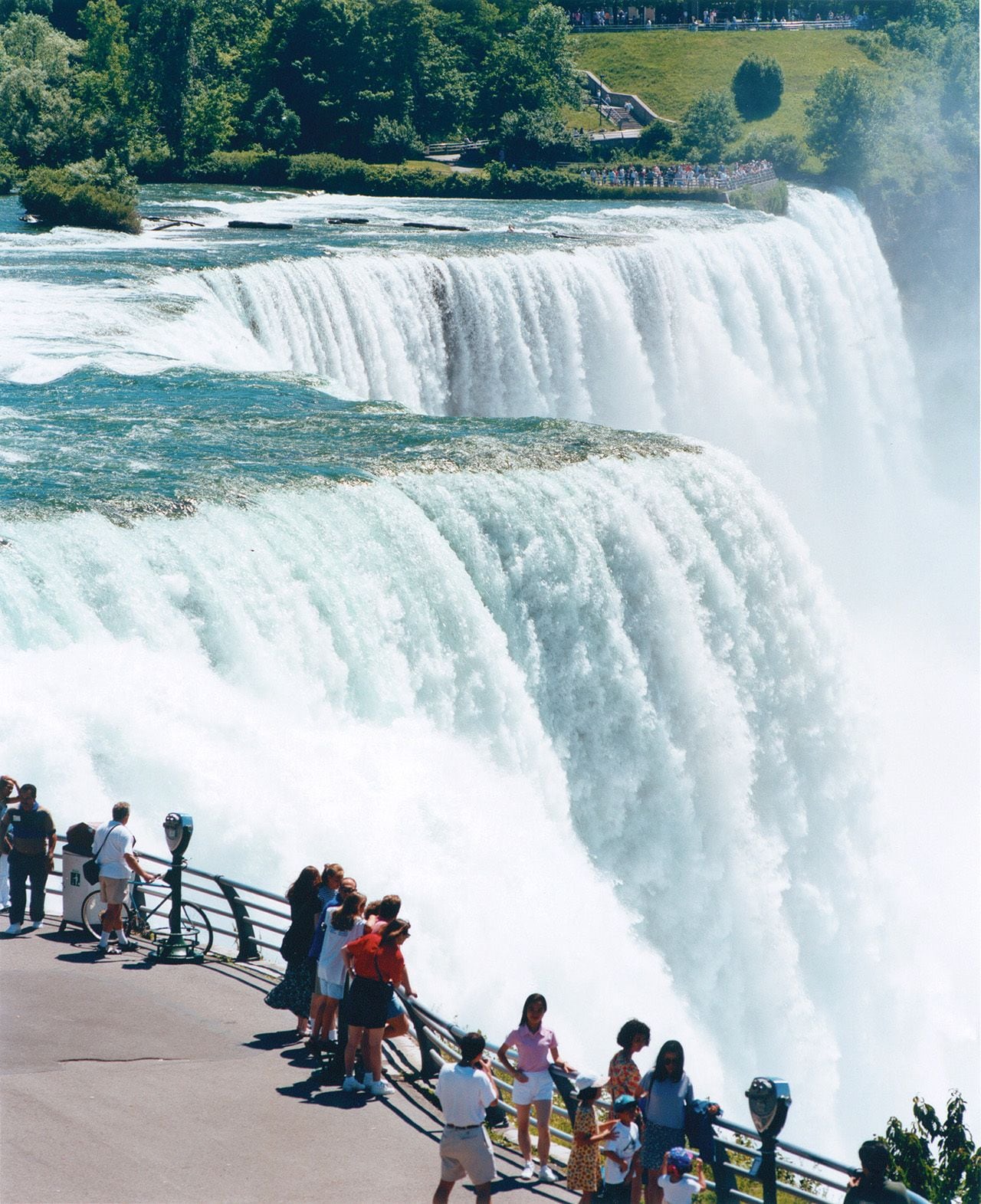 Una cascada imponente con una plataforma de observación y gente contemplándola.