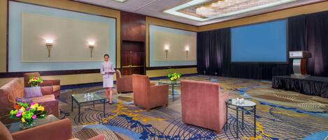 A spacious lobby with plush seating, a stage, and a large screen.