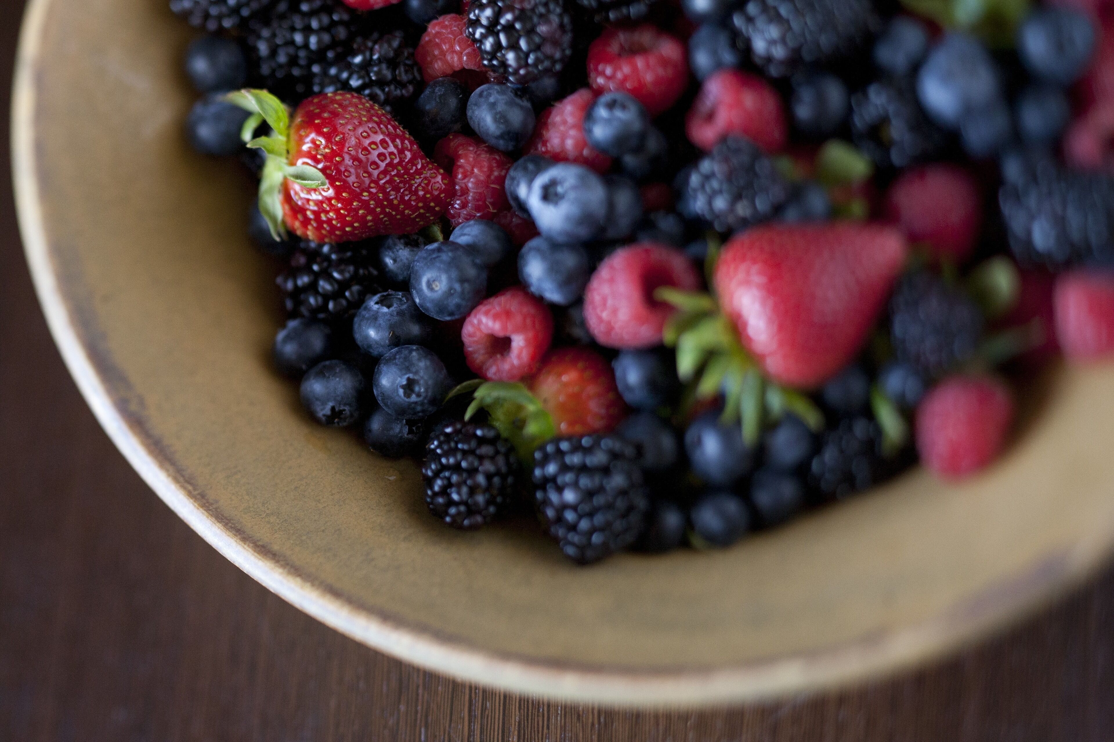 A bowl filled with various berries including strawberries, blueberries, and raspberries.