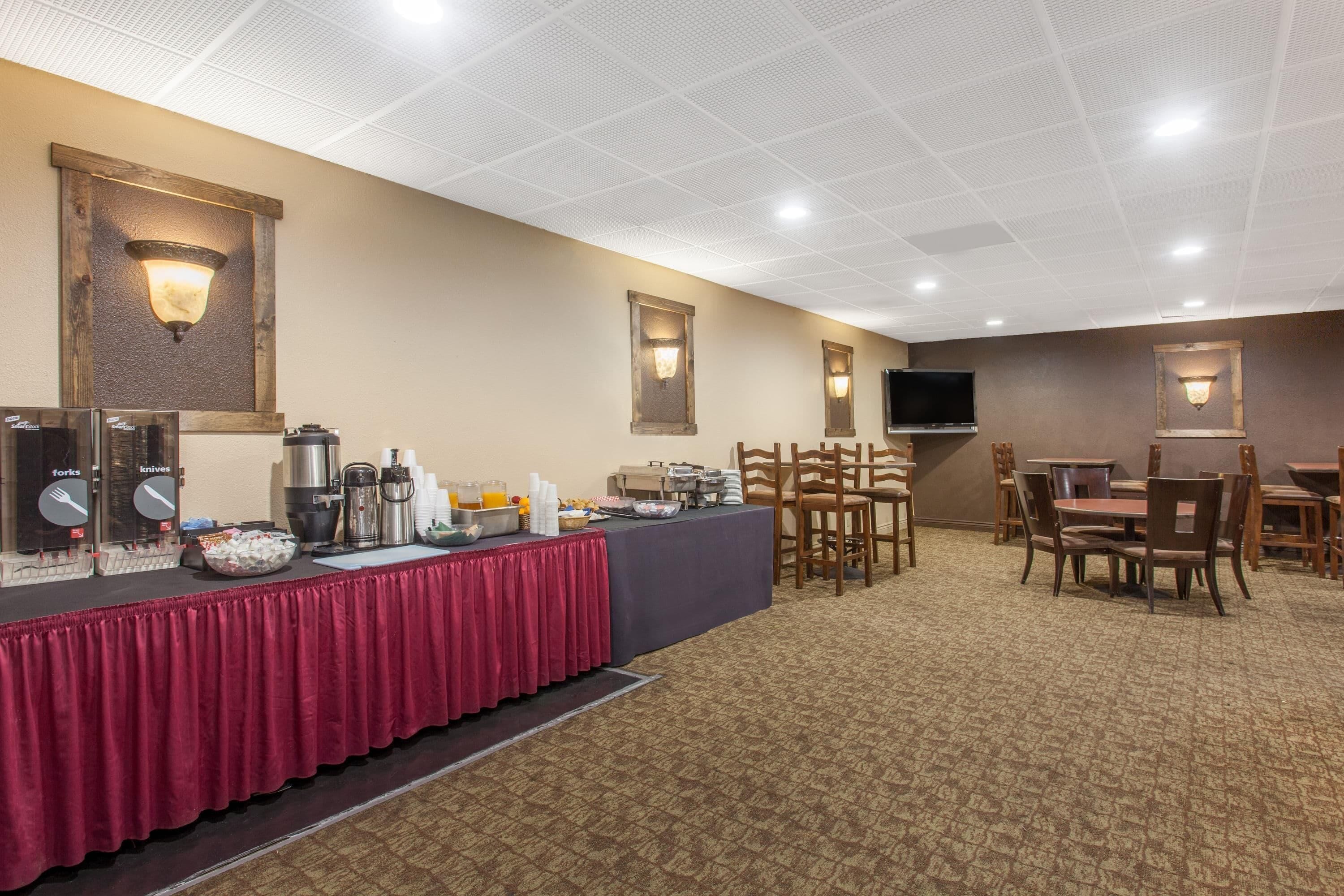 Un salón de conferencias con una larga mesa, sillas, un televisor y una mesa de buffet.