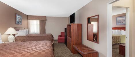 A hotel room with two beds, a desk, a chair, a TV, and a mirror.