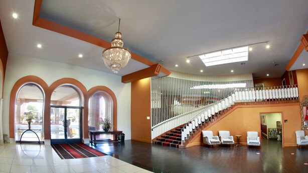 Eine großzügige Lobby mit einer imposanten Treppe, einem Kronleuchter und einer Sitzecke.