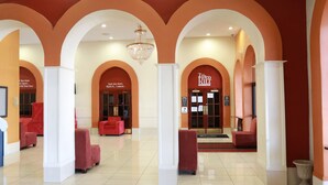 Eine geräumige Lobby mit roten Sitzgelegenheiten, weißen Säulen und einem Kronleuchter.