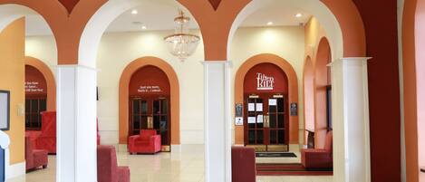 A spacious lobby with red seating, white columns, and a chandelier.